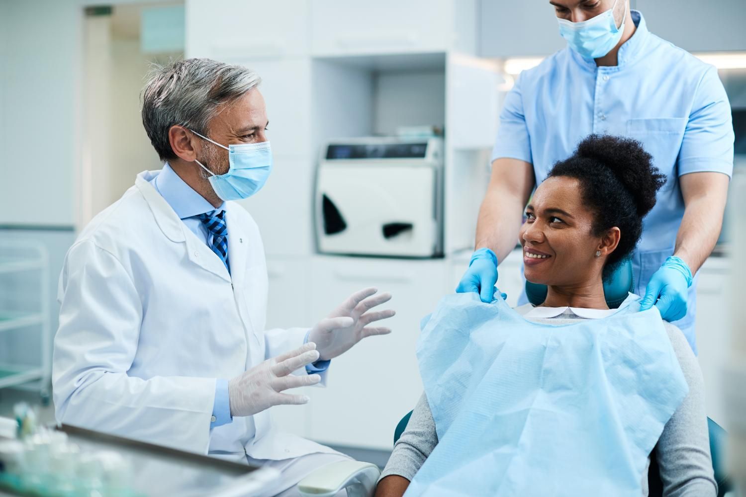 A woman is sitting in a dental chair talking to a dentist.