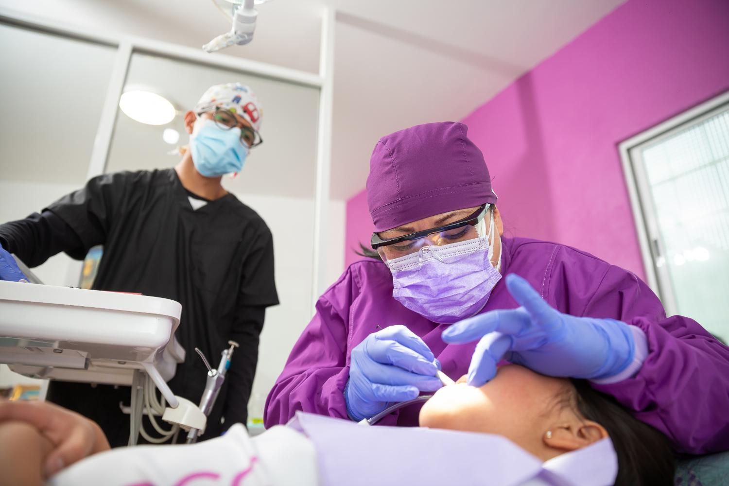 A dentist is examining a patient 's teeth in a dental office.