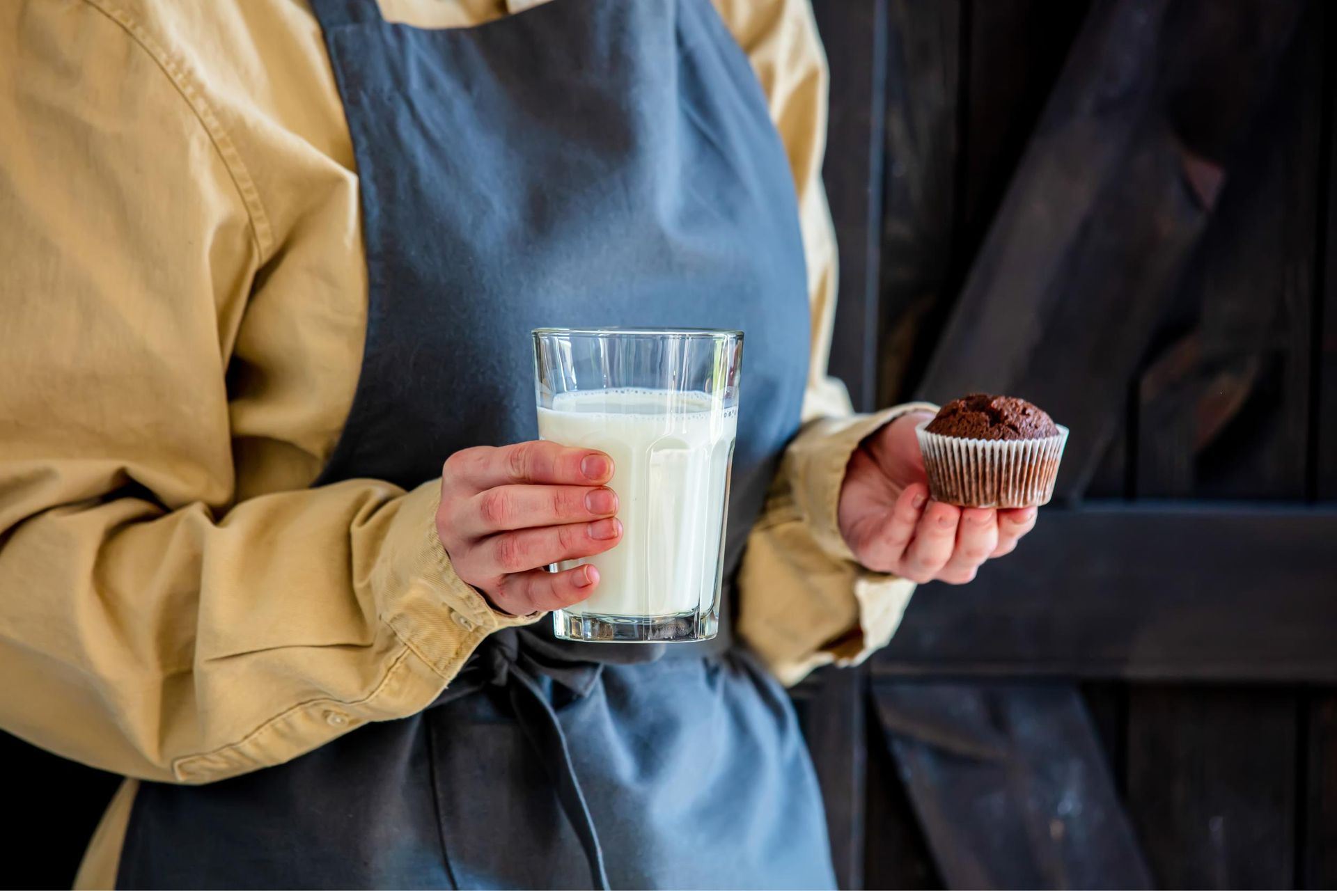 holding a glass of milk and a muffin