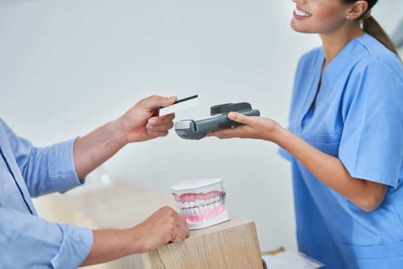 A man is paying for a dental treatment with a credit card.