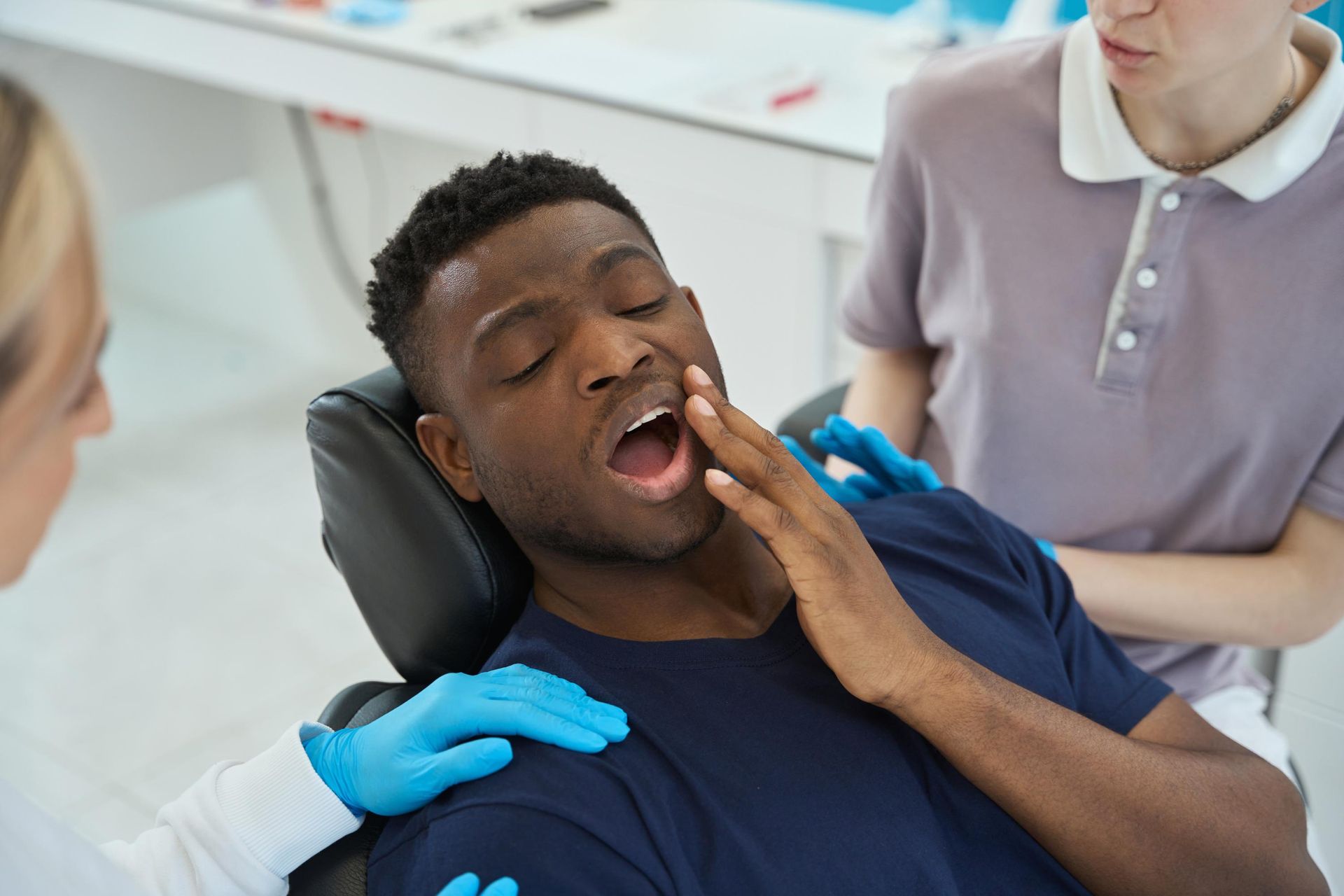 A man is sitting in a dental chair with his mouth open.