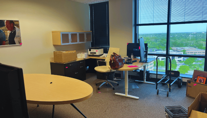 An empty office with a table and chairs and a large window