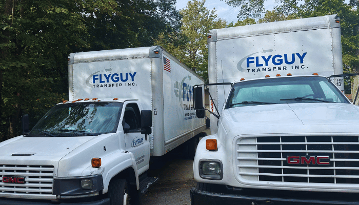 Two moving trucks are parked next to each other in a driveway.