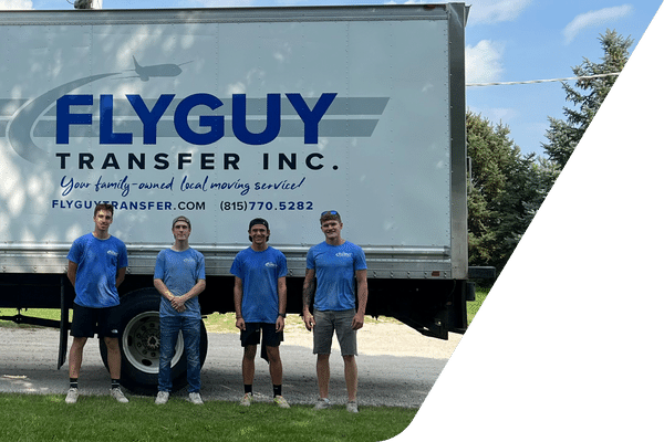 A group of men are standing in front of a truck that says flyguy transfer inc.