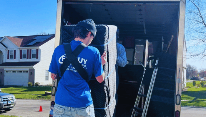 A man in a blue shirt is loading a refrigerator into a moving truck.