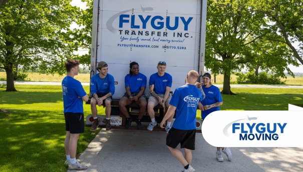 A group of men are standing in front of a flyguy moving truck.