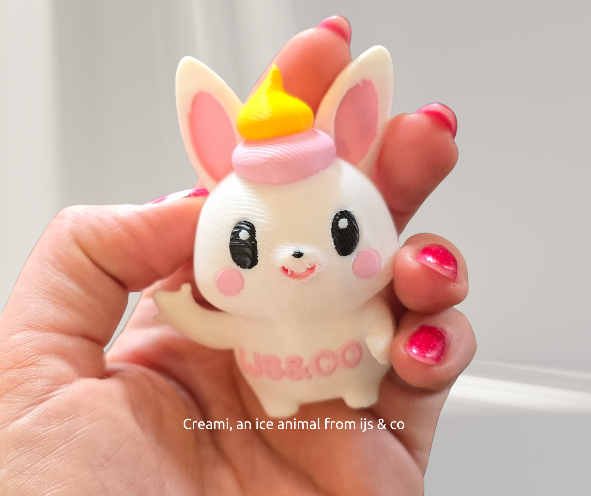 Hand holding a white bunny figurine with pink cheeks, hat, and waving paw.