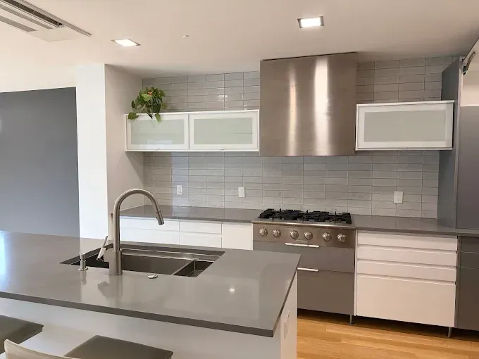 Modern kitchen with gray countertops, stainless steel appliances, and white cabinets.