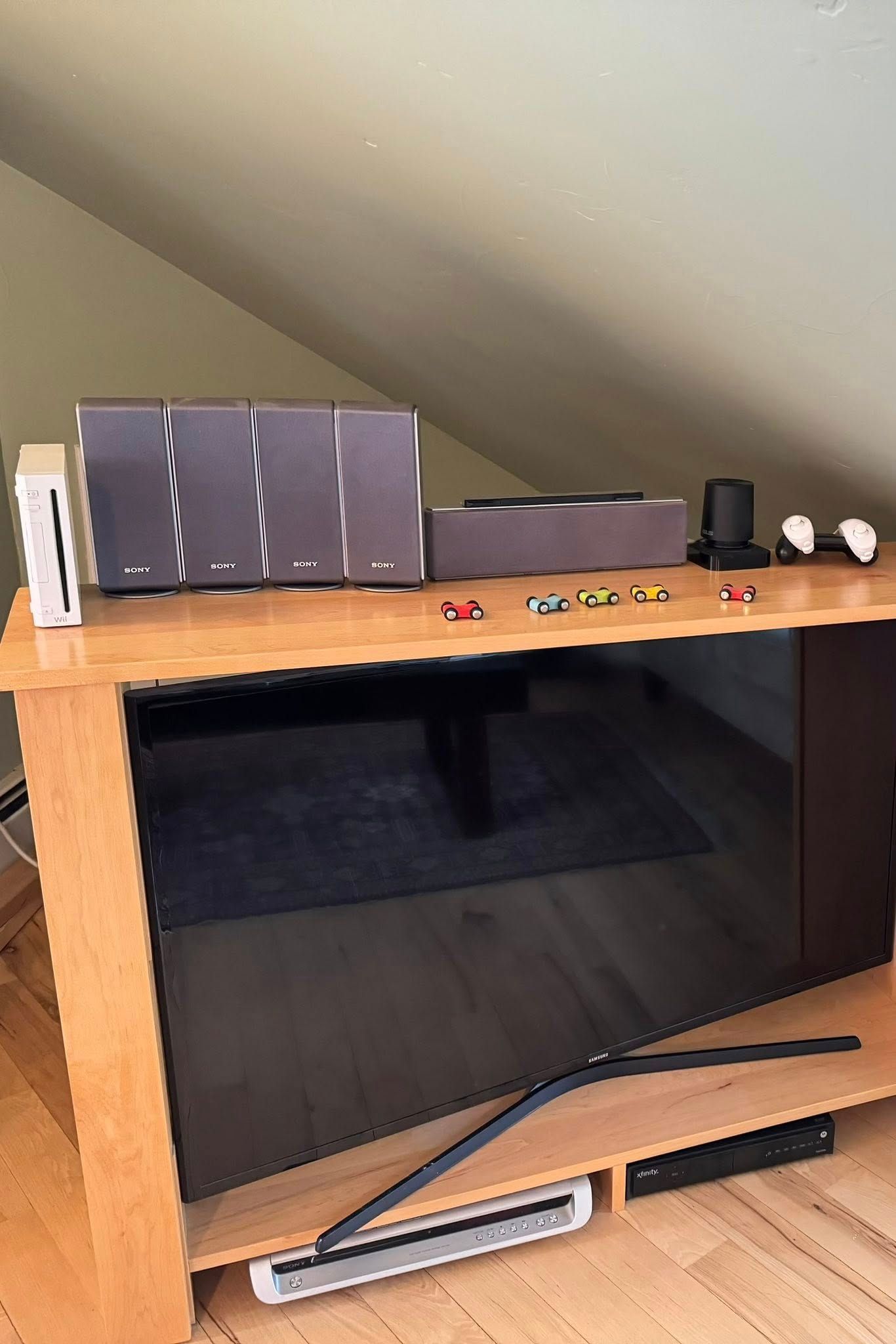 TV on a wooden stand with a Wii console, speakers, and small toys.