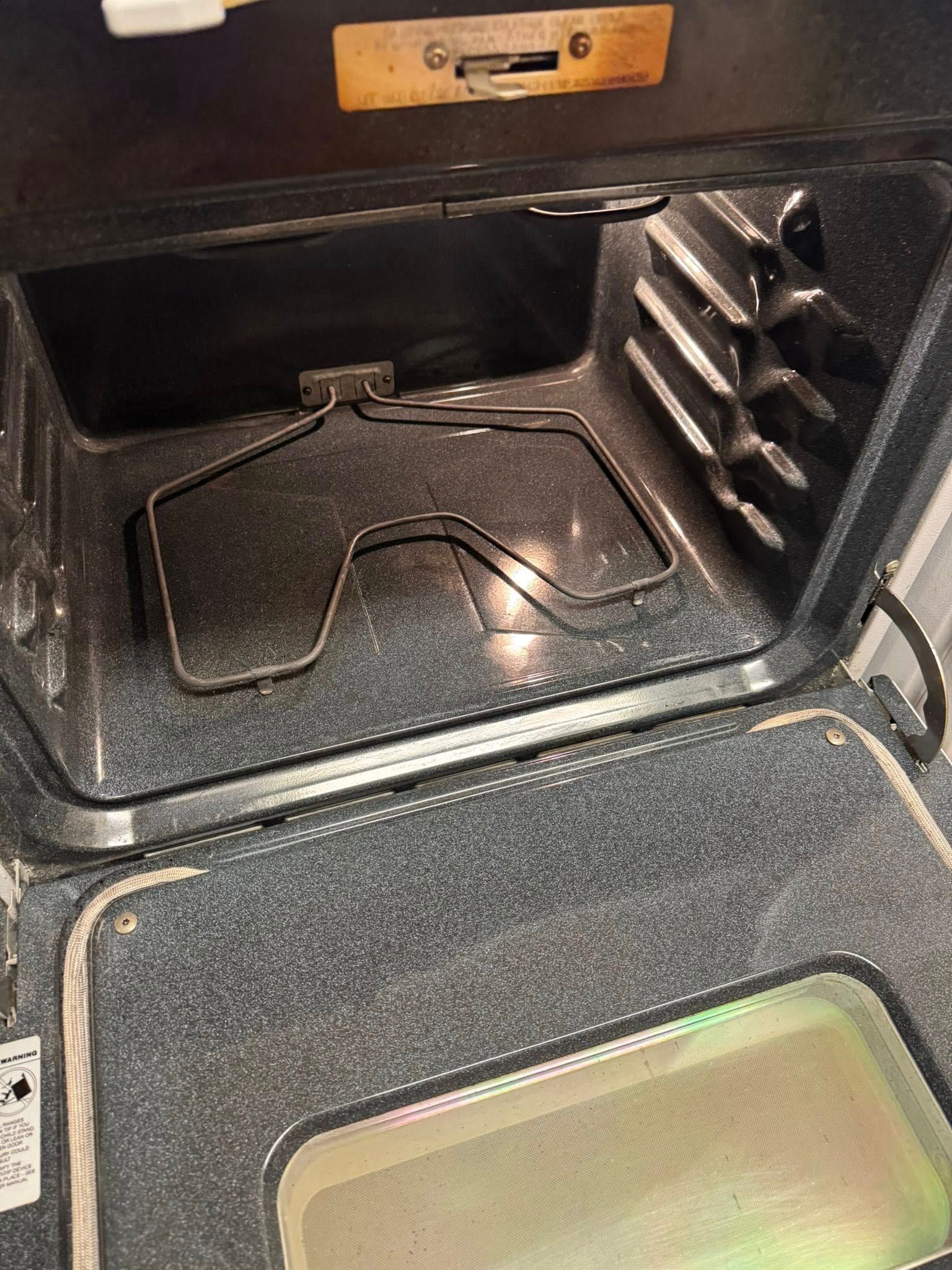 Interior of an oven with a rack. The inside is dirty with a glass door and controls above.