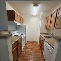 Kitchen with white appliances, wooden cabinets, and a stove.