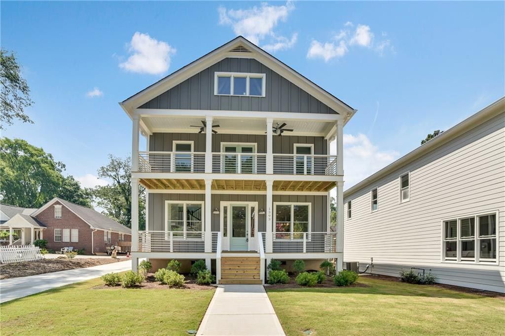 Two-story house with gray siding and multiple balconies on a bright sunny day.