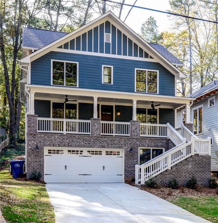 Two-story blue house with white trim, brick facade, and a two-car garage. A staircase leads to the front porch.