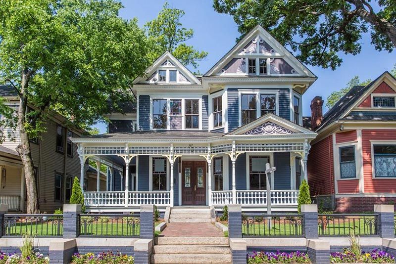 Blue Victorian house with white trim, porch, and a brick pathway.