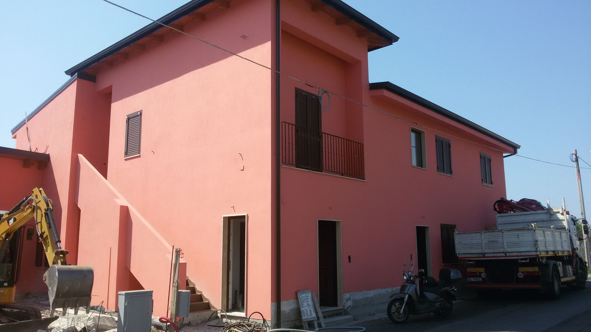 Un edificio rosa con una moto parcheggiata davanti