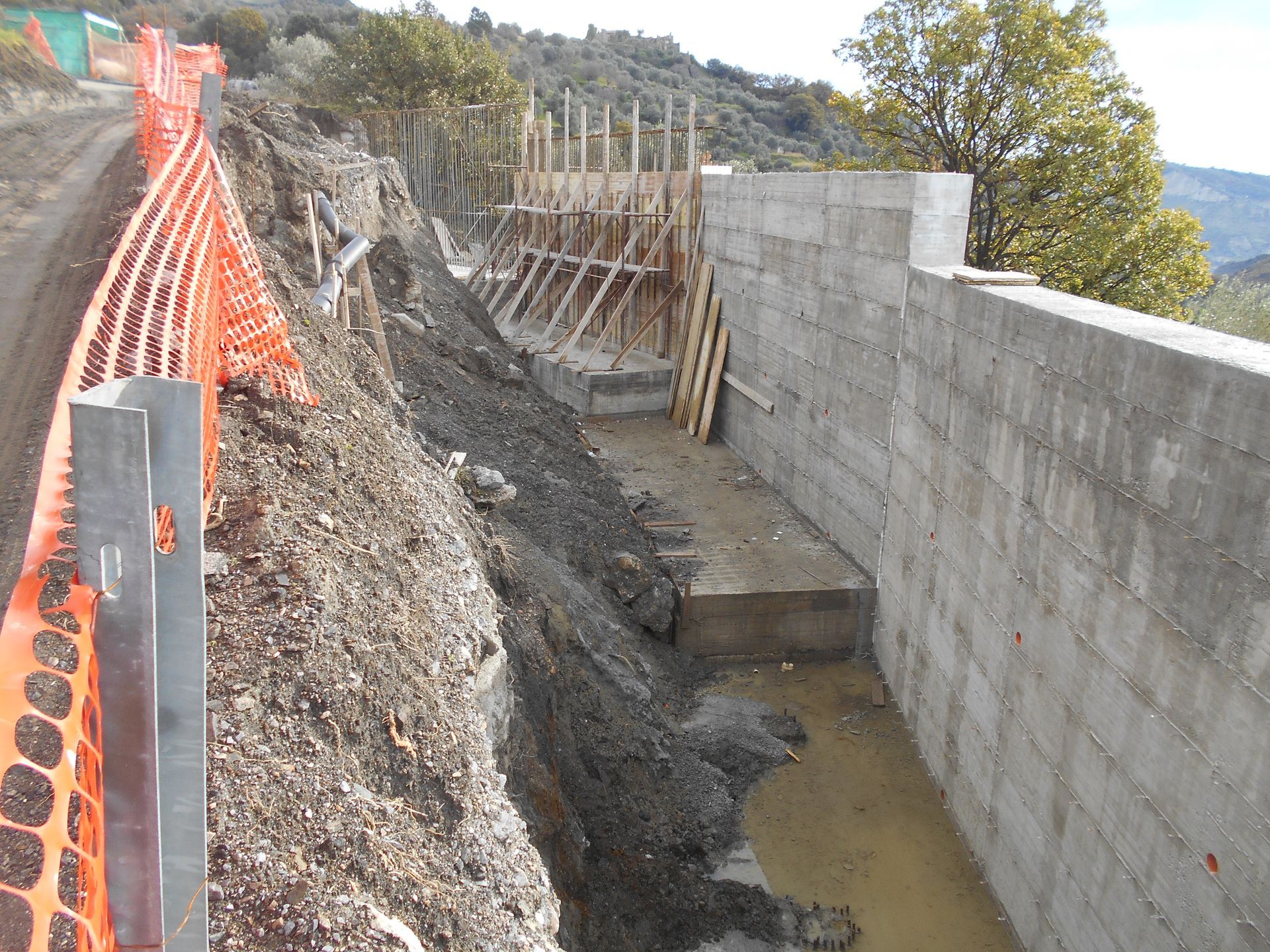 Un muro di cemento viene costruito accanto a una strada sterrata
