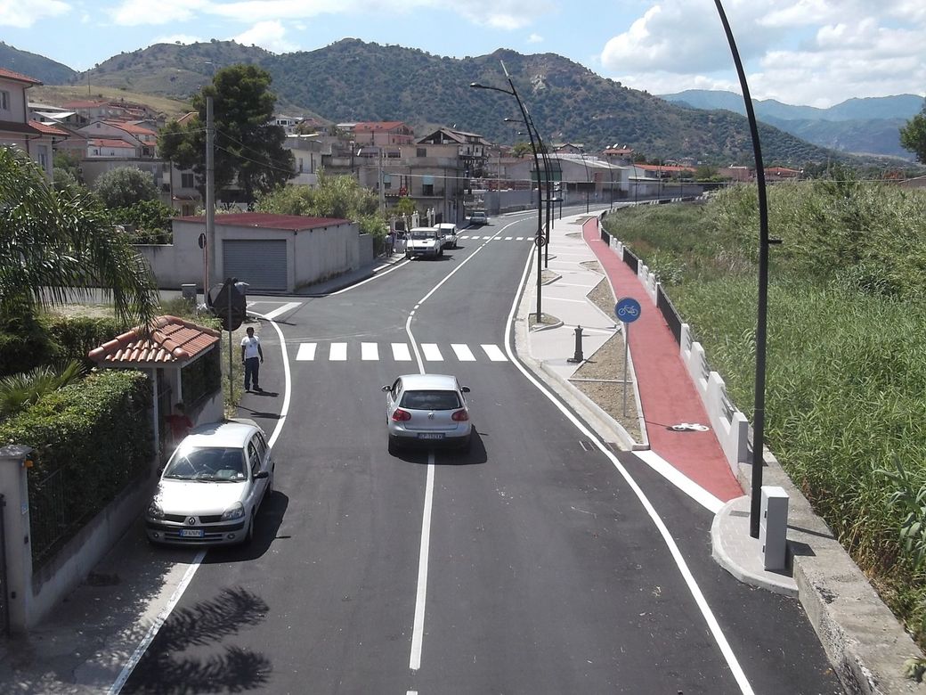 Un'auto bianca sta percorrendo una strada con le montagne sullo sfondo