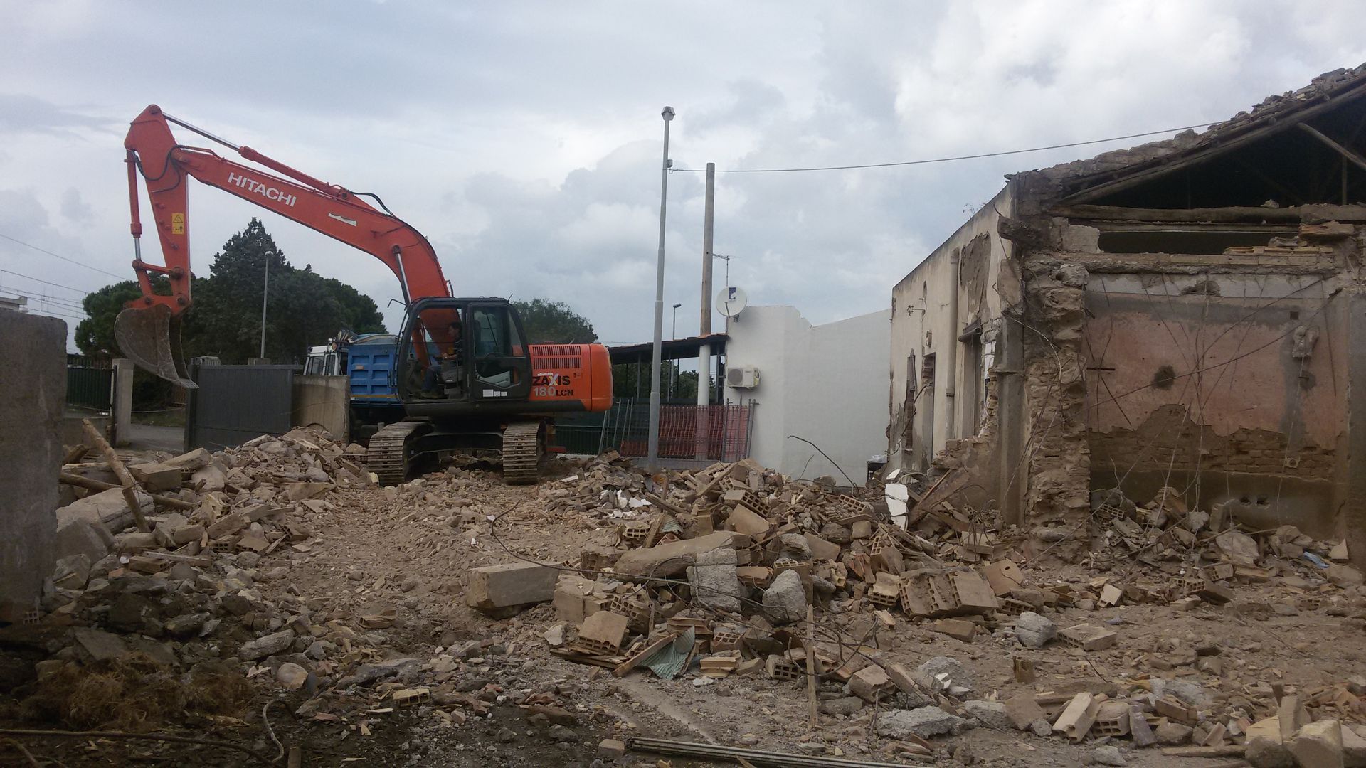 Un grande escavatore sta demolendo un edificio in un campo.