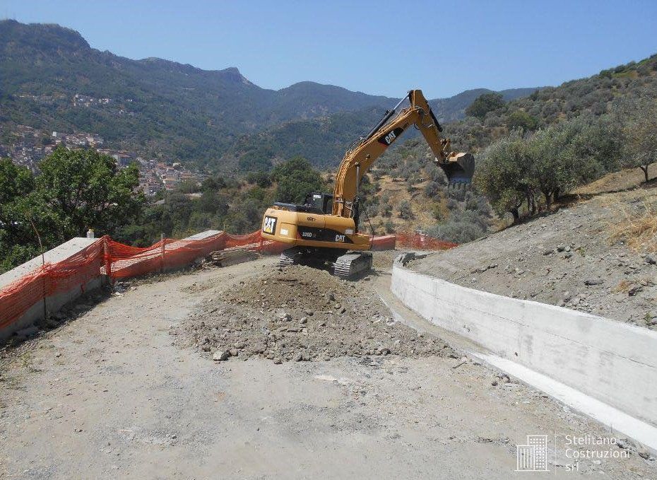 Un escavatore a gatto sta lavorando su una strada in montagna
