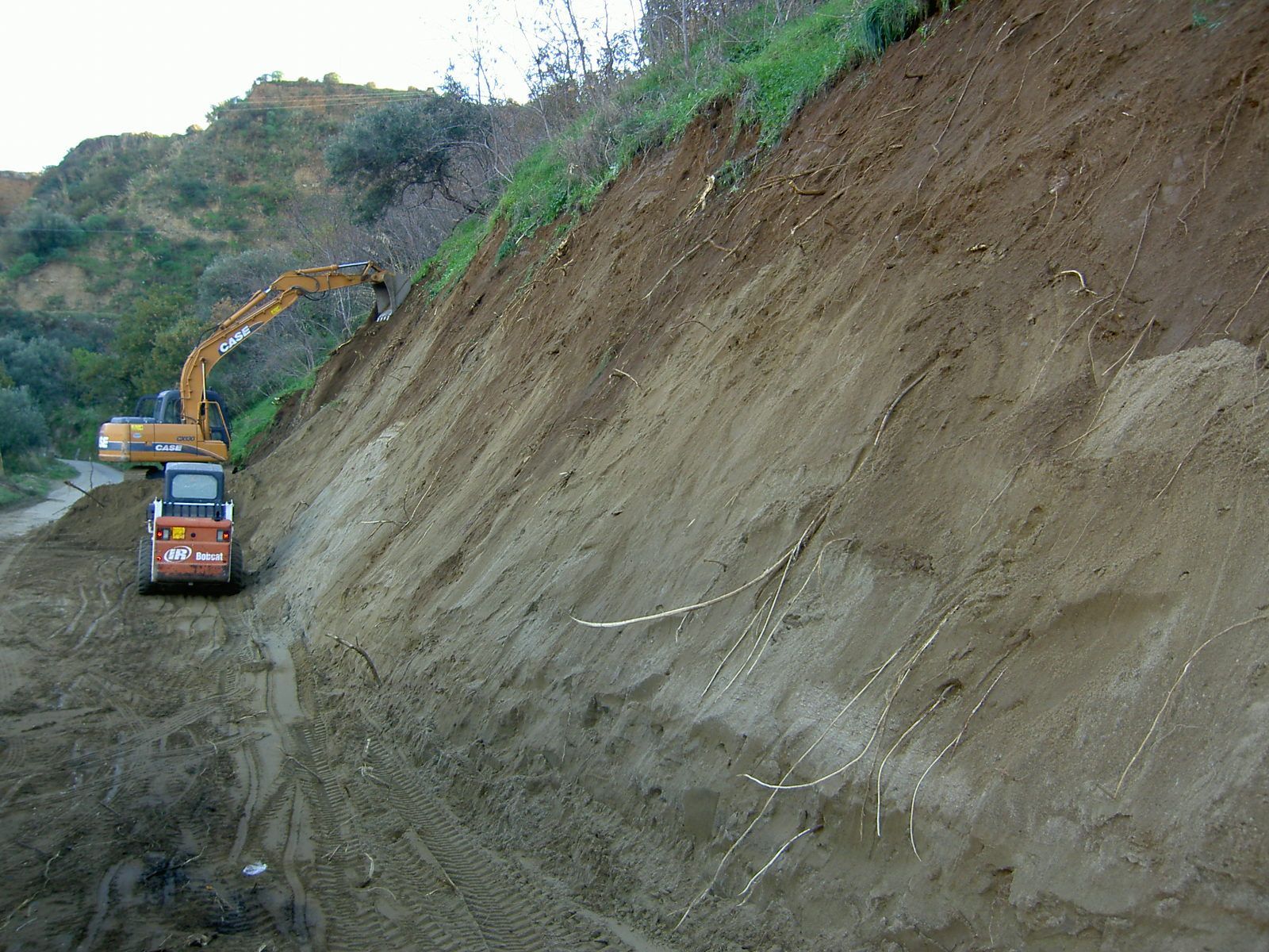 Un grande escavatore sta lavorando su un pendio sterrato