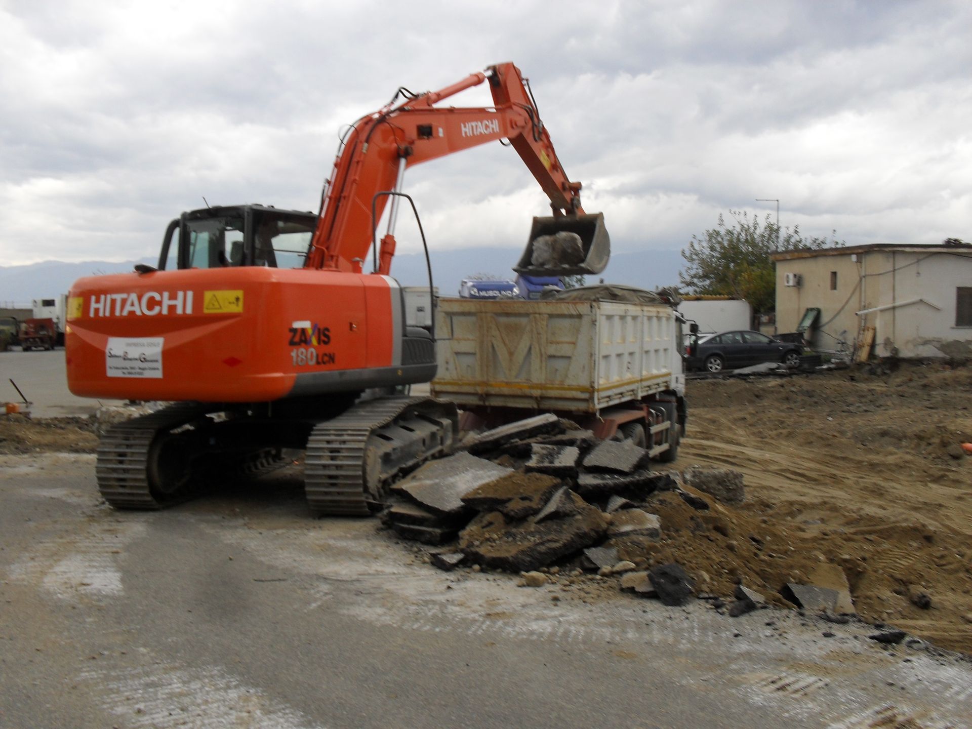 Un escavatore Hitachi sta caricando terra in un cassonetto