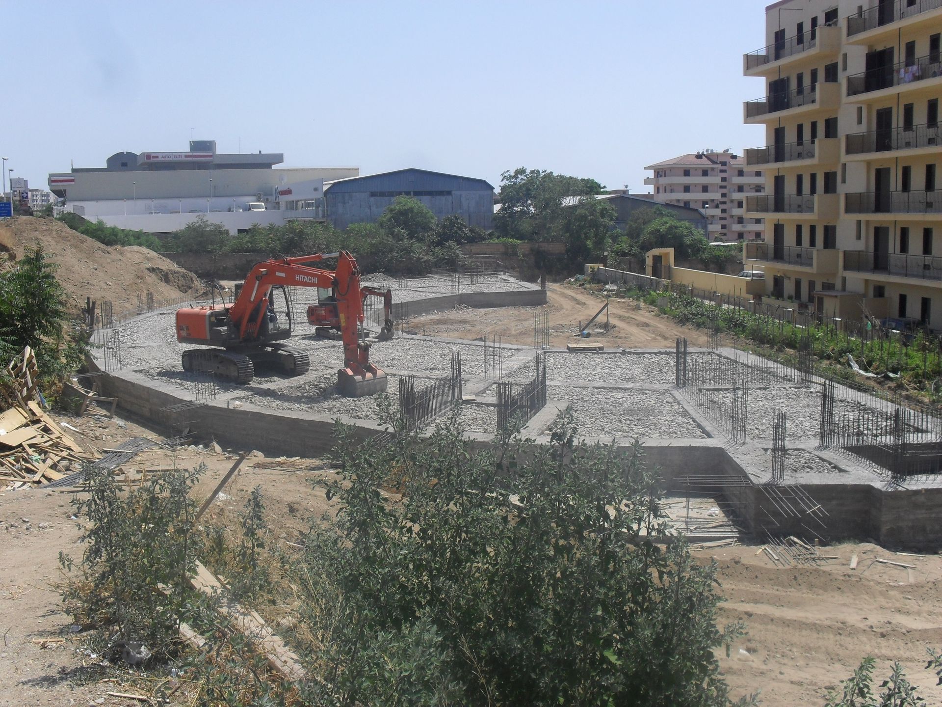 Un cantiere con un grande escavatore arancione in primo piano