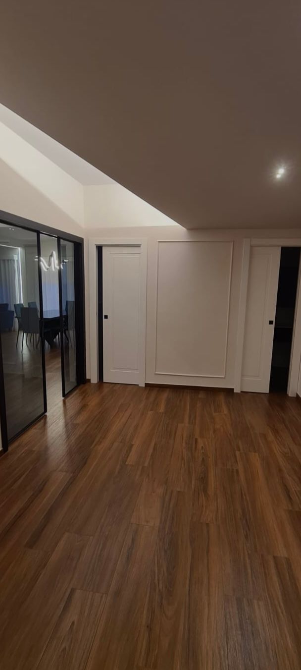 Una grande stanza vuota con pavimenti in legno e pareti bianche.