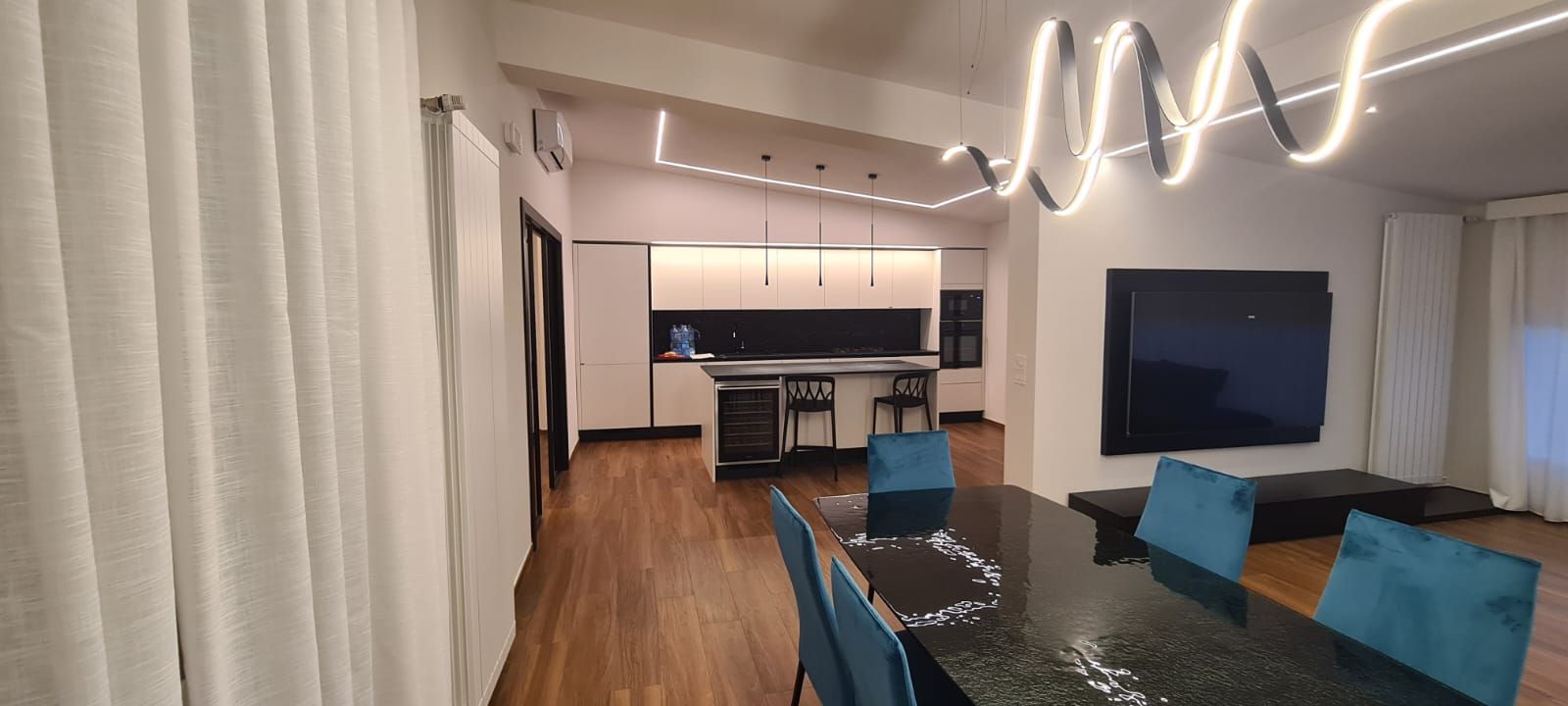 Un soggiorno con tavolo da pranzo, sedie e televisione.