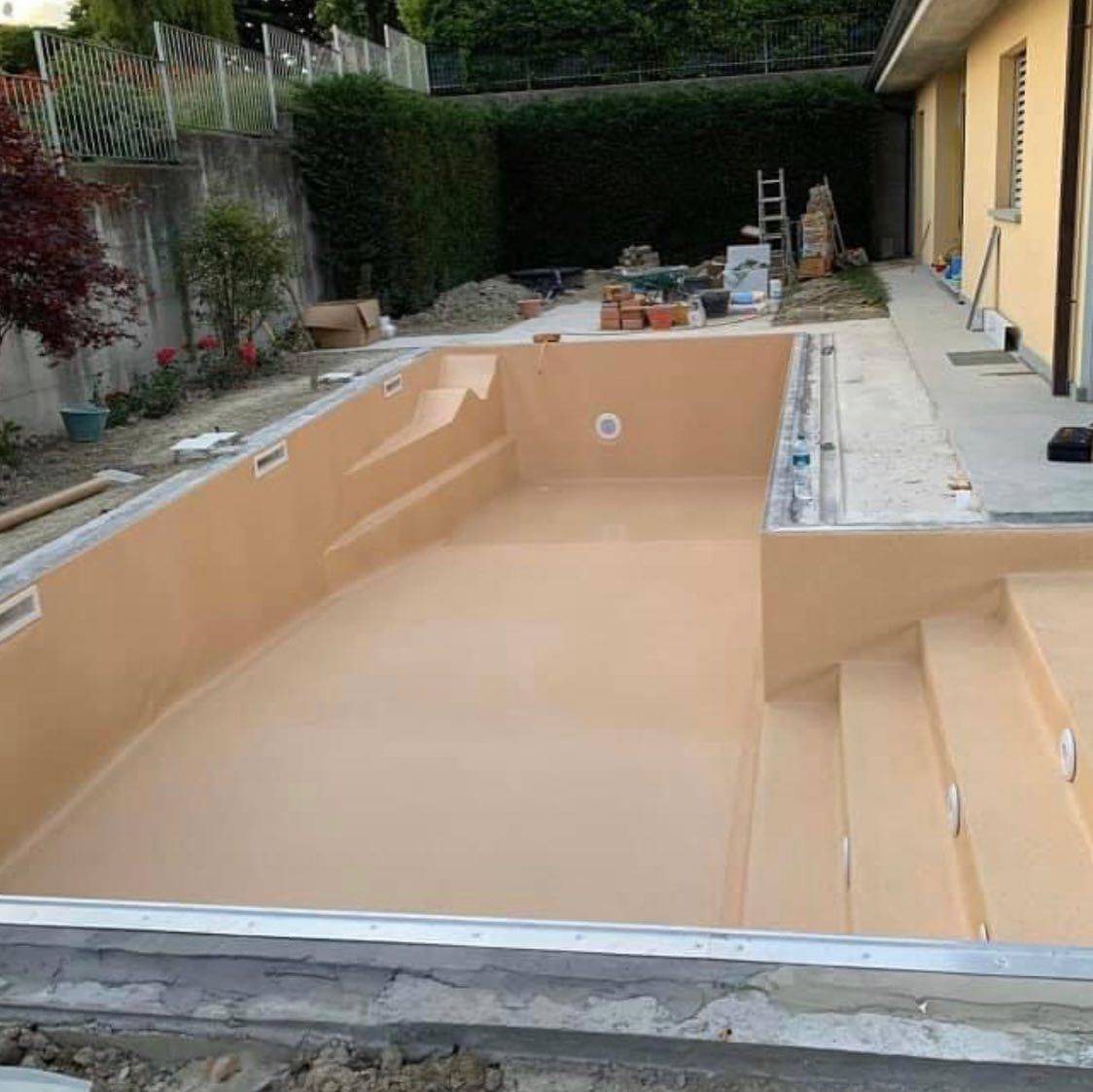 Nel cortile di una casa è in costruzione una grande piscina.