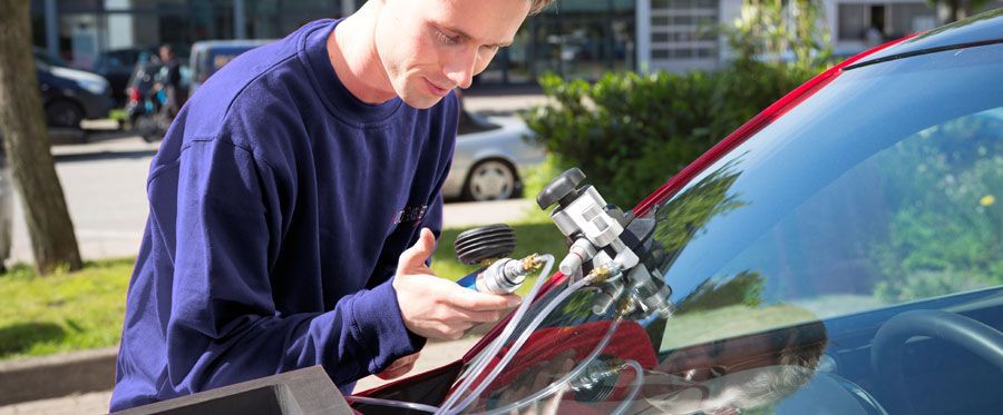 A man is fixing a windshield on a car.