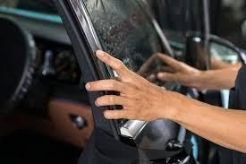 A person is applying tinted glass to a car window.