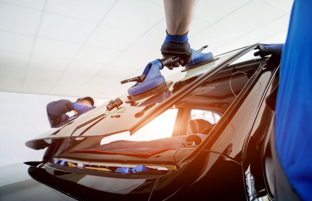 A man is installing a windshield on a car.