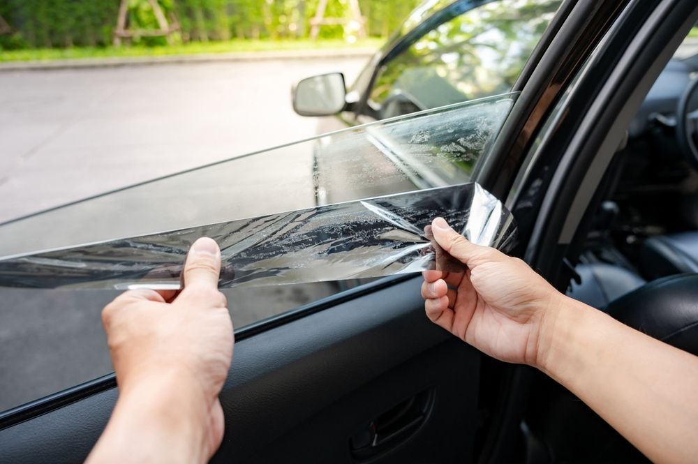 A person is applying window tinting to a car window.