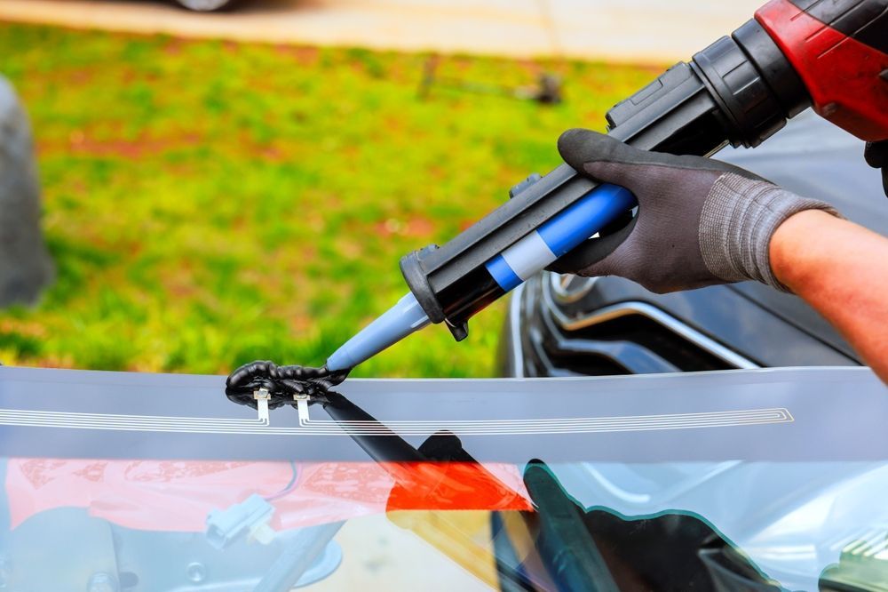 A person is applying silicone to a windshield of a car.