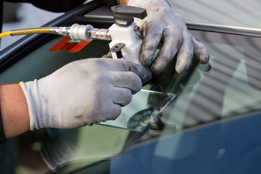 A person is repairing a windshield on a car.