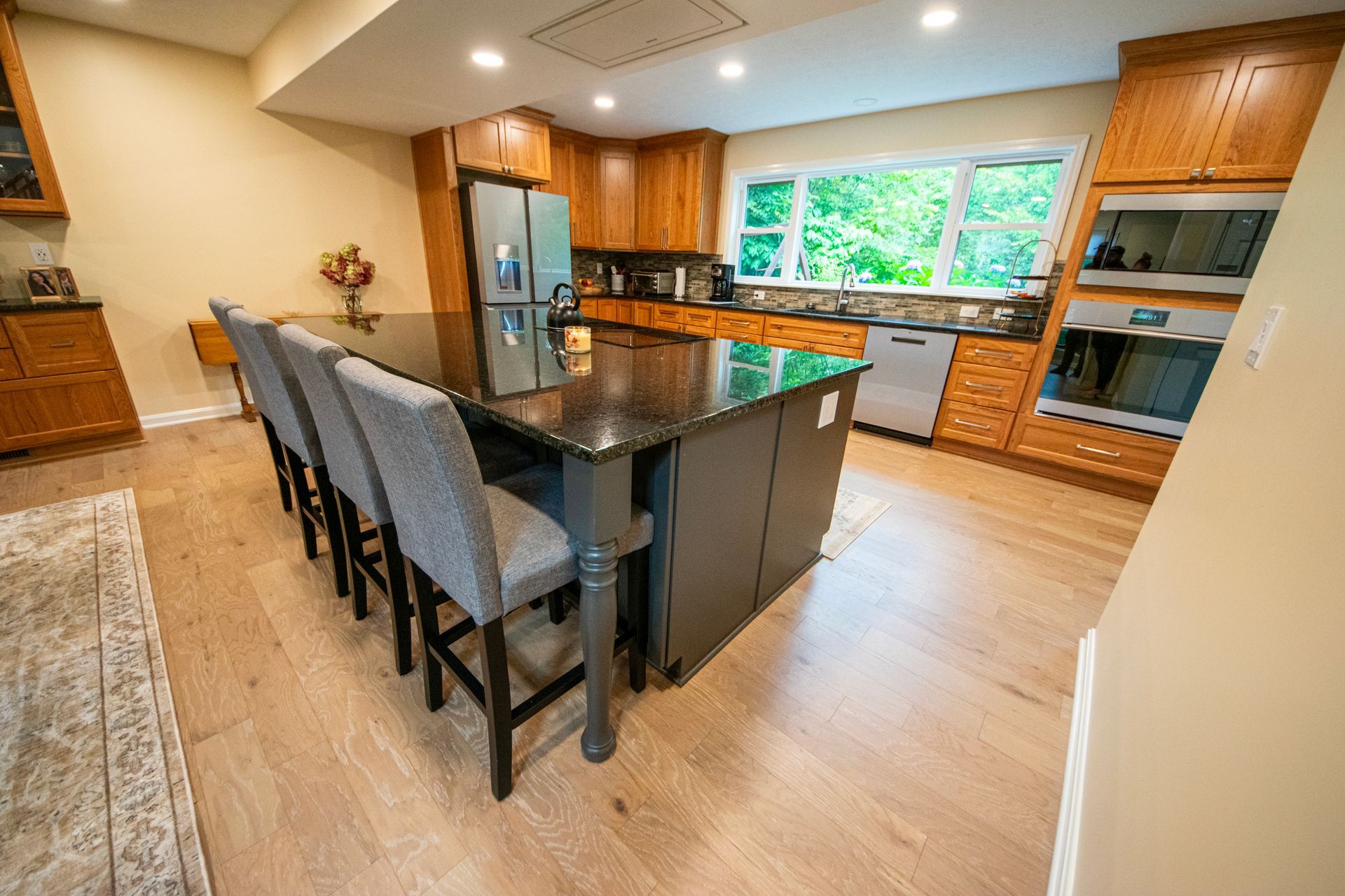 Spacious kitchen with large island, granite countertop, and seating, hardwood floors, and wood cabinetry.