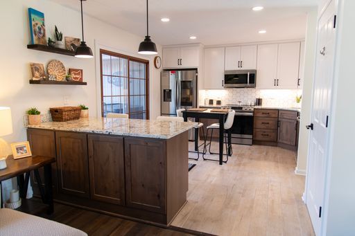 Modern kitchen with white and dark wood cabinets, island, and stainless steel appliances.