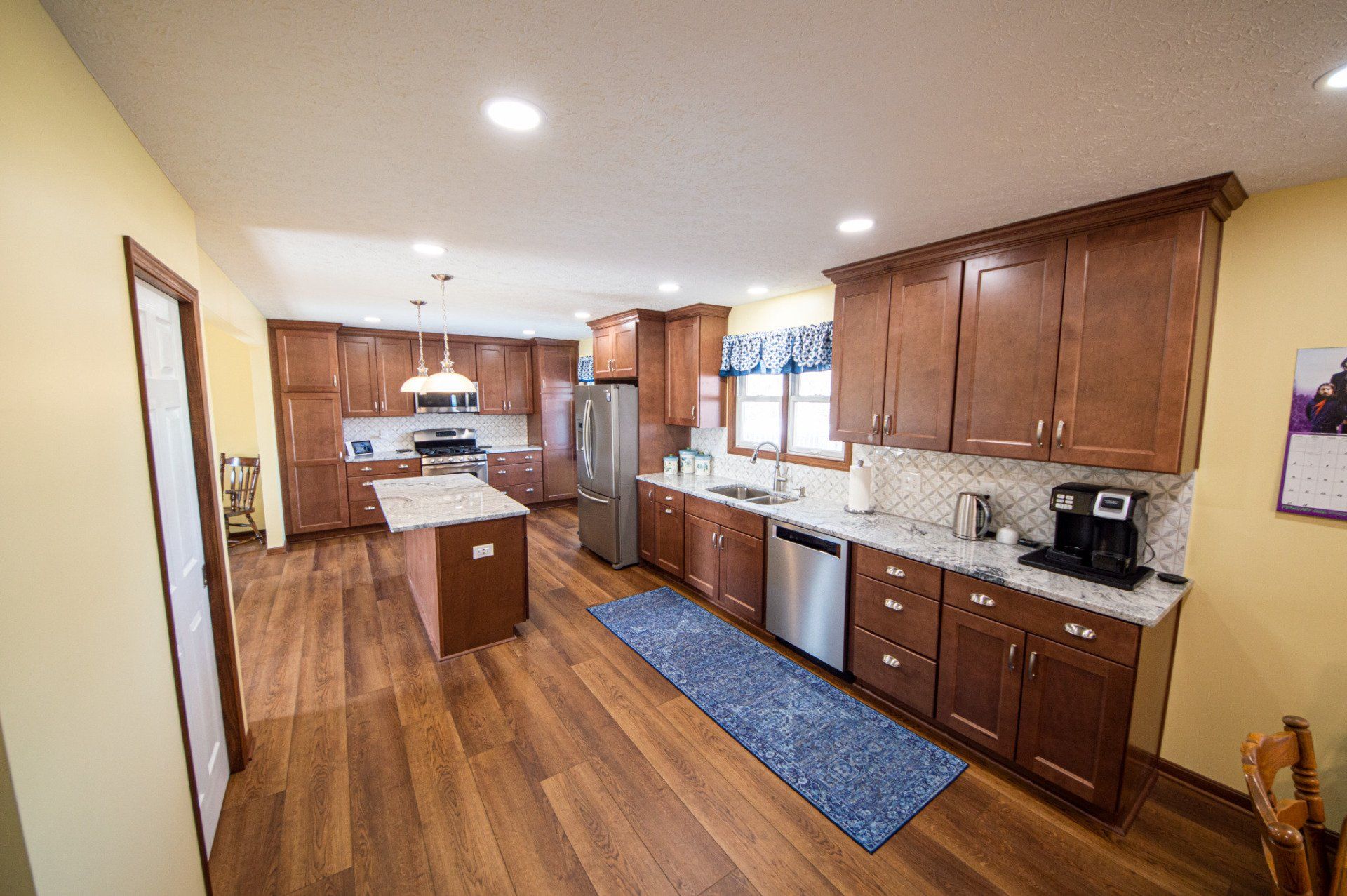 Spacious kitchen with brown cabinets, stainless steel appliances, and a wooden floor.