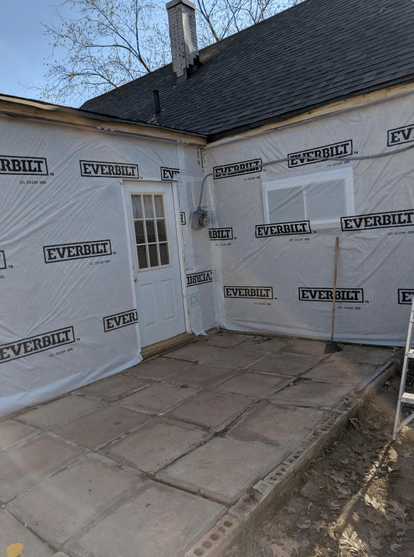 Exterior wall of a building with a door, window, the wall is wrapped in weather-resistant barrier.