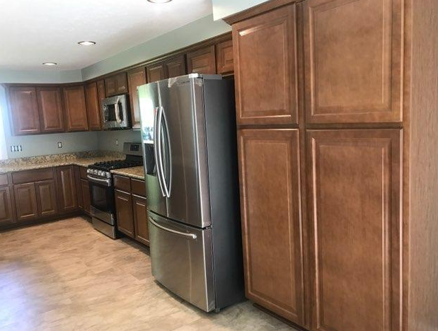 Kitchen with brown cabinets, stainless steel appliances, and a light-colored tiled floor.