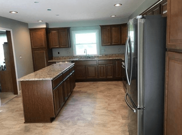 Kitchen with brown cabinets, granite countertops, stainless steel appliances, and island.