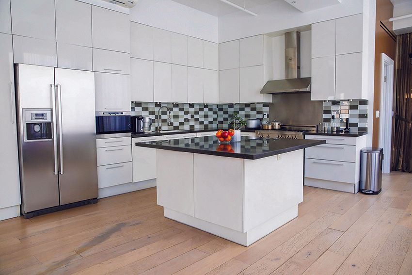 Modern white kitchen with stainless steel appliances and a black countertop island.