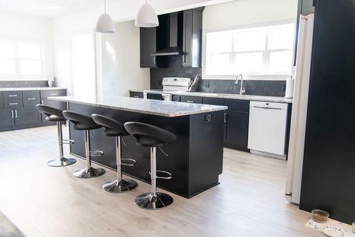 Modern kitchen with dark cabinets, light countertops, and an island with stools.