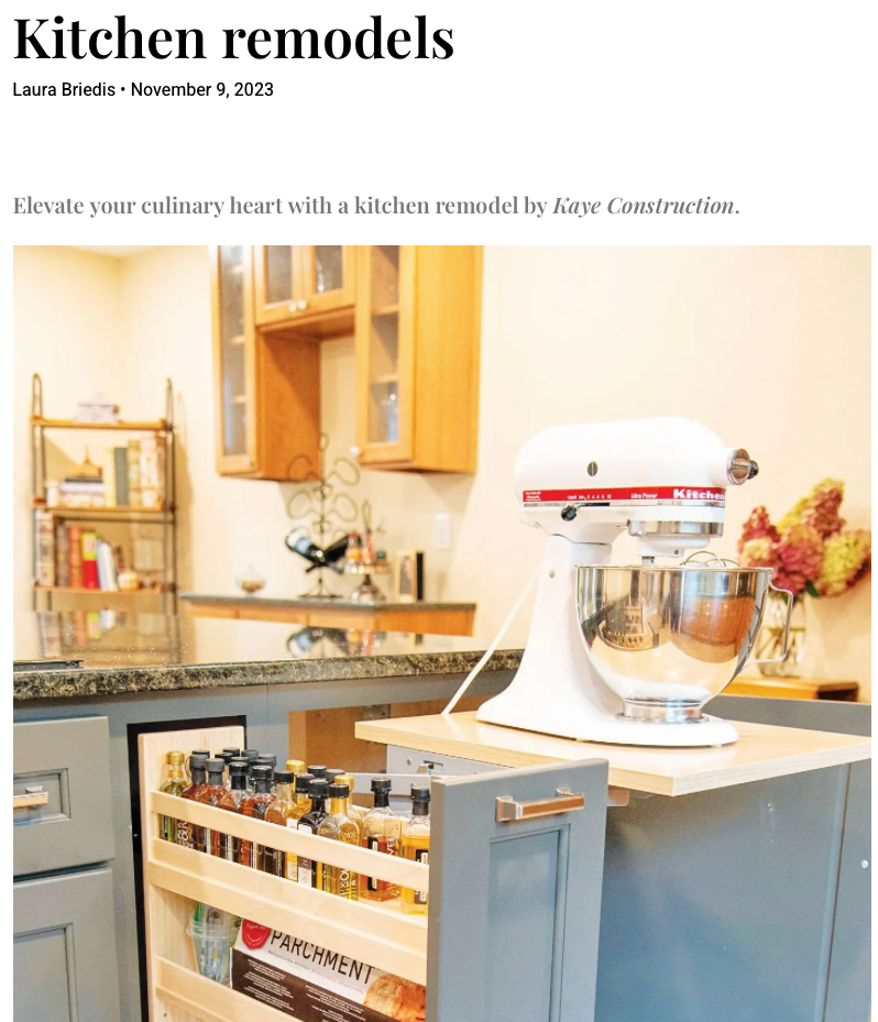 Kitchen with pull-out spice rack and stand mixer on a countertop. Blue cabinets, light wood shelves.