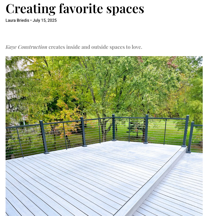 Deck overlooking a green yard, with a dark railing and trees in the background.