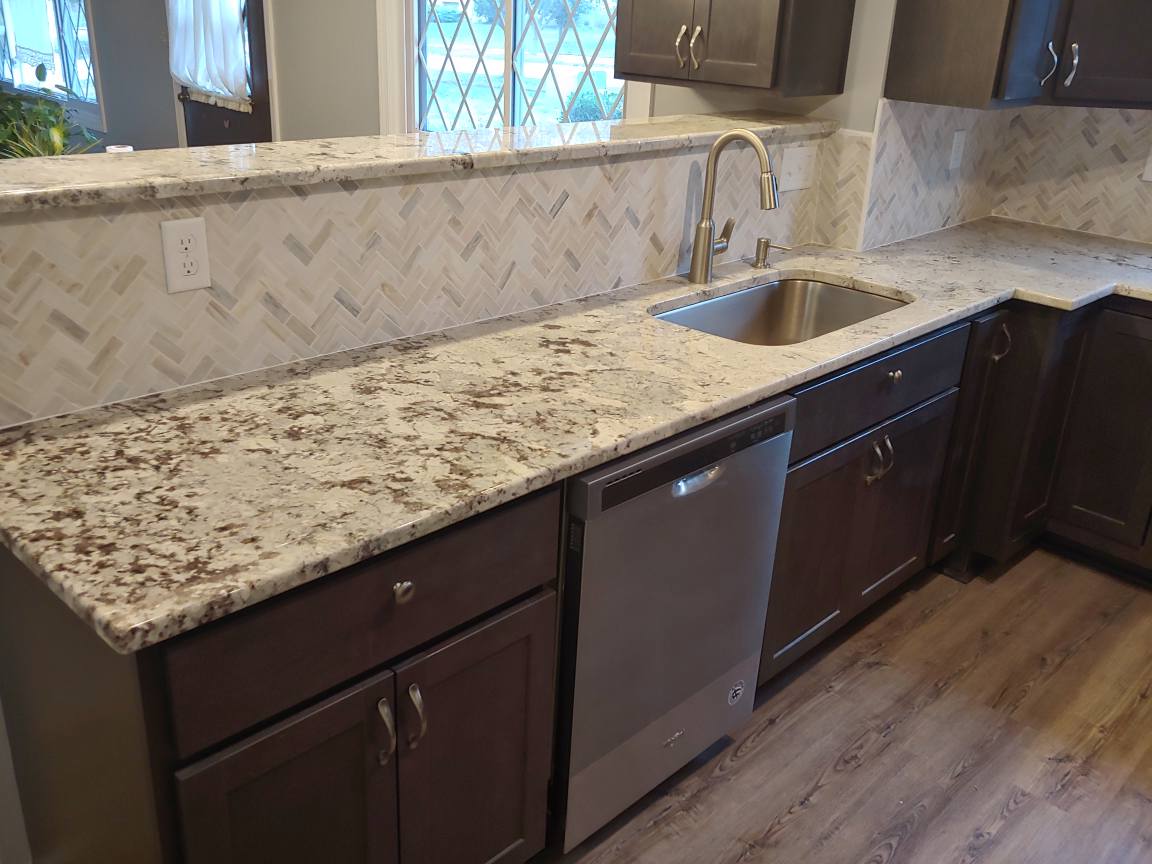 Dark-brown kitchen cabinets with granite countertops and a stainless steel sink and dishwasher.