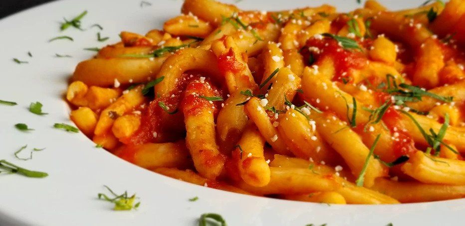 A white plate topped with pasta and tomato sauce.
