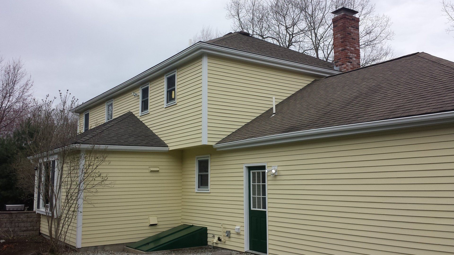 a large yellow house with a brown roof and a chimney.