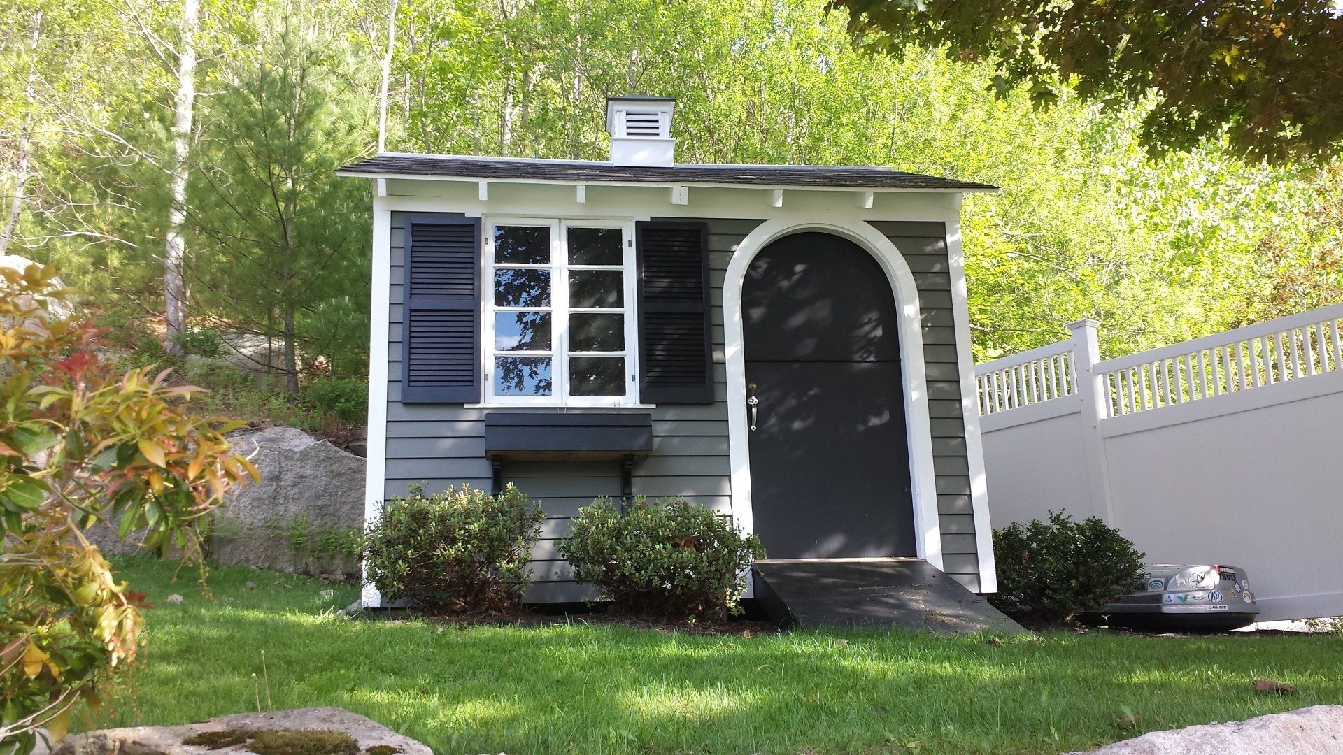 a small house with a white fence in front of it