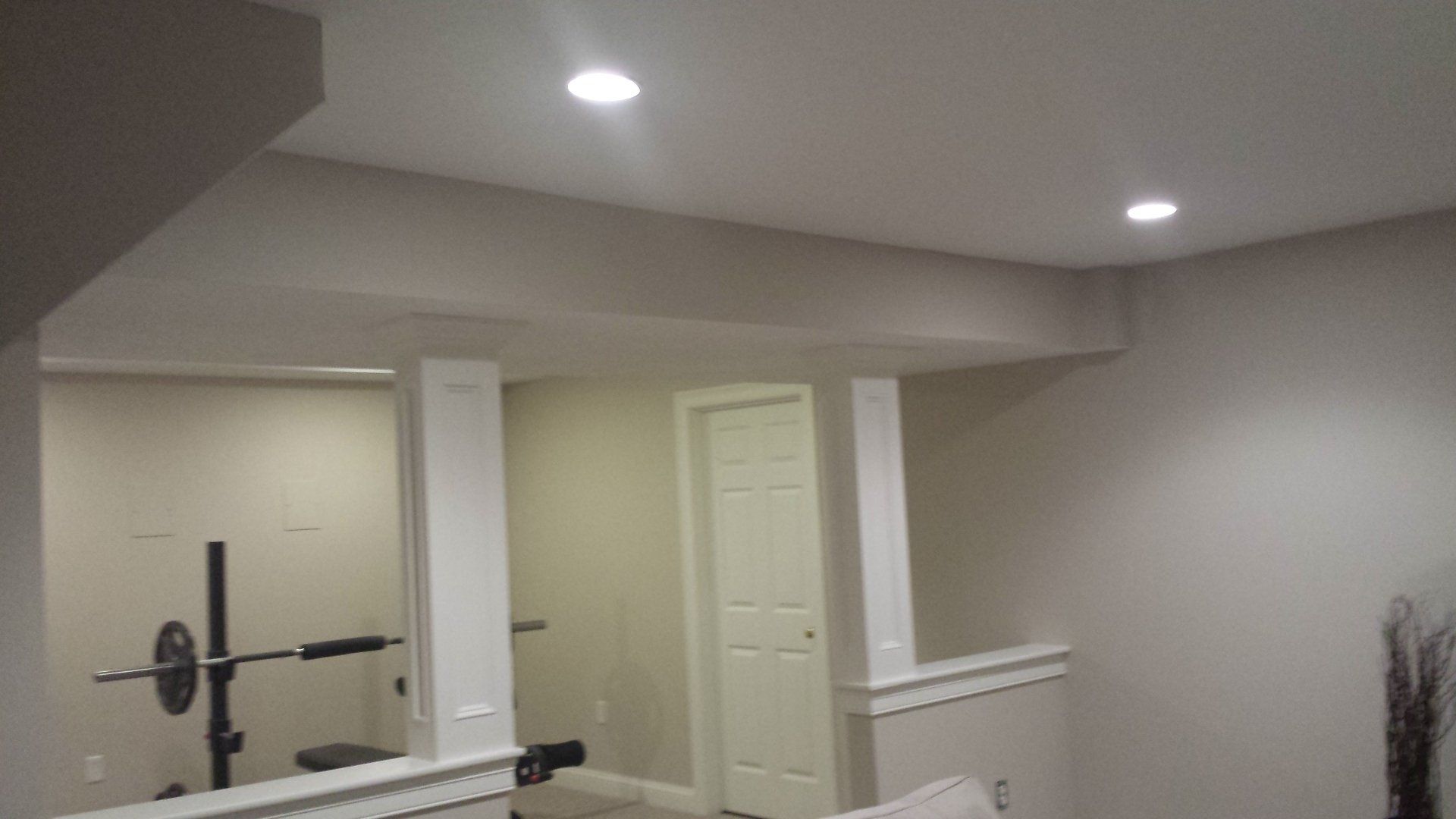 a basement with a couch and a barbell on the wall.